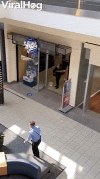 Man Casually Strolls Past Woman Pointing Gun Inside Mall
