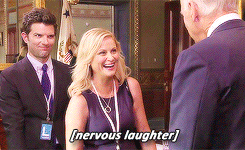 Parks and Recreation gif. Amy Poehler as Leslie and Adam Scott as Ben are talking to someone and looking very uncomfortable and awkward. Leslie laughs stiffly and shakes their hand and the text reads, "nervous laughter."
