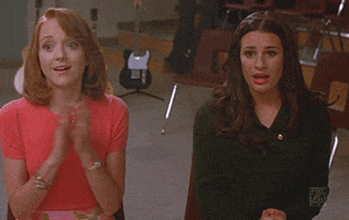 TV gif. Lea Michele as Rachel Berry and Jayma Mays as Emily Pillsbury in Glee applaud, moved.