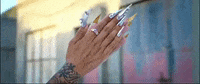 Music video gif. From Rosalía's video for Aute Cuture, two hands with long, sharp chrome nails clap.