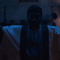 Movie gif. Eddie Murphy as Rudy Ray Moore in Dolemite Is My Name walks up to a microphone and the spotlight with his arms stretched wide in the air. He looks around with a smile at the audience in front of him.