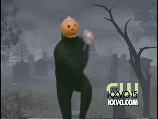 Video gif. Pumpkin Dance man in a black unitard with a jack-o-lantern on his head does dances from side-to-side in front of a graveyard backdrop. 
