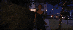 Movie gif. Emma Stone as Mia from La La Land runs down a sidewalk at night with a giddy smile, holding out her dark green dress by the skirt.
