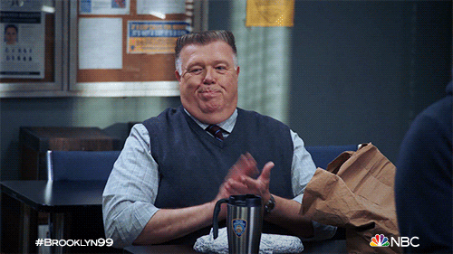 TV gif. Joel McKinnon Miller as Scully on Brooklyn Nine-Nine sits in the break room with his lunch in front of him. He looks around the room with an unimpressed smirk and slowly claps.