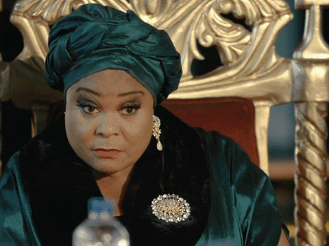 Movie gif. Sola Sobowale as Eniola Salame on King of Boys sits in a throne with wide eyes, then blinks hard as if to reset, then looks off to the side while speaking. Text, "Anyway..."