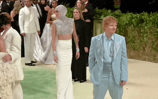 Met Gala 2024 gif. Ed Sheeran poses awkwardly in a baby blue tuxedo, Cara Delevigne and Stella McCartney posing expertly and enthusiastically behind him.