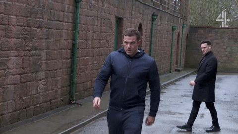 TV gif. Jamie Lomas as Warren and Maxim Baldry as Liam face off in an argument set in an alleyway.