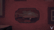 Video game gif. A man in a jacket is standing with his back facing the camera while lights flash and lightning strikes in the background. The man quickly and dramatically turns around and holds up an unidentified object in his right hand.