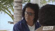 Reality TV gif. Gene Simmons sticks his tongue out in casual disgust, turning his head away.