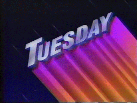 Text gif. Metallic purple title reading, "Tuesday" sits slanted while gradient magenta to orange streaks add colorful dimensionality to the text. Flashing bars going from light pink to purple pass through to further illuminate the word. The backdrop shows mini comets flying against a night sky.