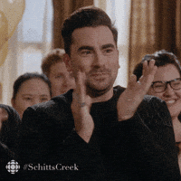 Schitt's Creek gif. Dan Levy as David claps his hands and pumps his fists, smiling with emotion in his eyes.