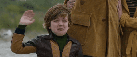 Video gif. A little boy crying while waving goodbye.