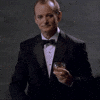 Celebrity gif. Bill Murray holds a glass of alcohol in his hand and points at us while lifting his eyebrow up. 