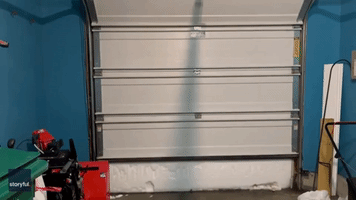 an Opens Garage Door to Reveal Wall of Snow