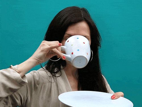 Video gif. Woman with hoop earrings sips a teacup with her pinky out. She looks very satisfied after her sip, as she closes her eyes in pleasure.