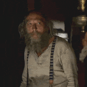 Video gif. An elderly man in suspenders smiles as he holds up two thumbs as if saying good luck. 