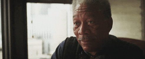 Movie gif. Morgan Freeman as Lucius Fox in the Dark Knight series smiles and tips his head to the side slightly and says, "good luck," which appears as text.