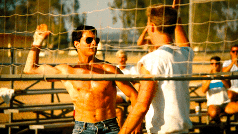 Movie gif. Actor Tom Cruise as Maverick in Top Gun high fives victoriusly then low fives his volleyball teammate Goose played by Anthony Edwards. 