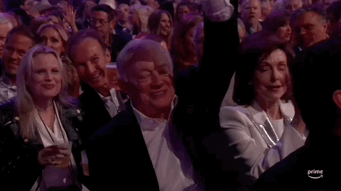 TV gif. An older gentleman in the audience at the 2024 ACM Awards happily raises his hand, then pumps his fist, happy to be recognized.