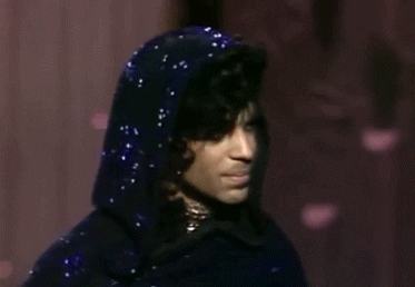 Celebrity gif. Prince wears a sparkly hood and turns his back to us.