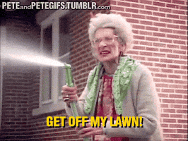 Animated GIF of elderly woman spraying a hose at kids offscreen and shouting, "Get off my lawn!"