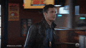 TV gif. Andy Samberg as Jake Peralta on Brooklyn Nine-Nine goes up to a bar and without even looking at him, high fives Joe Lo Truglio as Charles Boyle. Charles does a small spin as he high fives Jake.