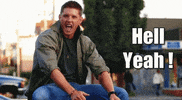 Video gif. Man rolls his shoulder excitedly, doing a little dance, sitting by the street. Text reads, "Hell Yeah!"
