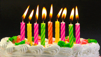 Animated graphic gif. Closeup image of the top of a birthday cake with white frosting and colorful candles that dance and flicker.