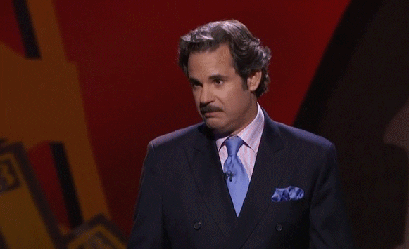 Celebrity gif. Wearing a dark blue suit with a light blue tie, Paul F. Tompkins recoils in disgust, then gives a playful thumbs-down.
