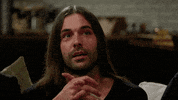 Reality TV gif. Jonathan Van Ness from Queer Eye is sitting with his hands folded together and he slowly purses his lips and raises his eyebrows, shaking his head slightly in acknowledgment, but not agreeing or disagreeing.