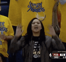Sports gif. Ayesha Curry stands in a crowd of Warriors fans and claps as she cheers, saying, "Let's go!"