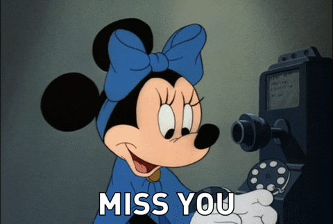 Disney gif. A vintage cartoon of Minnie and Mickey Mouse. Minnie talks into an old pay phone speaking to Mickey, who is sitting cozily in an armchair with an old home phone up to his ear. Mickey melts into his chair after hearing Minnie’s words. The text says: “Miss you” 