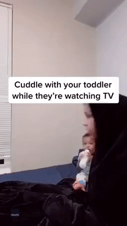 Minneapolis Mother Cuddles With Her Baby as He Watches TV