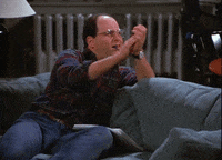 Seinfeld gif. Jason Alexander as George Costanza with a pen in his mouth, clapping sarcastically.