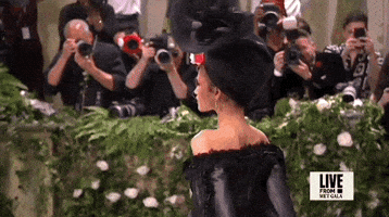 Met Gala 2024 gif. Zendaya, turns toward us, revealing her big floral hat.