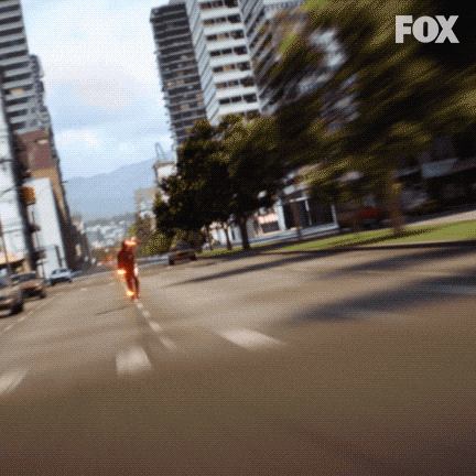 TV gif. The Flash running as fast as he can toward us down a city street, then passing us, leaving a trail of sparks behind him.
