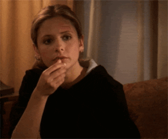 Celebrity gif. Sarah Michelle Gellar as Buffy Summers in Buffy the Vampire Slayer puts a piece of popcorn in her mouth, her expression blank.