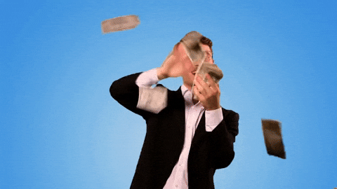 Video gif. A man in a business casual suit with a large smile on his face holds a stack of cash in his hand. He swipes the dollar bills off his hand and makes it rain money.