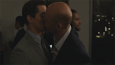 TV gif. Andrew Rannells as Elijah and Corey Stoll as Dill on Girls. Dill grabs Elijah by the neck and pulls him in for a passionate kiss. They pull back and Elijah smiles.