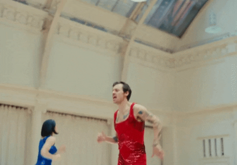 Music video gif. Harry Styles in As It Was jogs in place in a gym, singing as we move closer to him. 