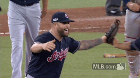 Sports gif. Cleveland Indians celebrate a play on the field and all run towards one another, huddling up and cheering. They rub each other's backs as their heads are tucked together and it's a great moment of teamwork and sportsmanship.