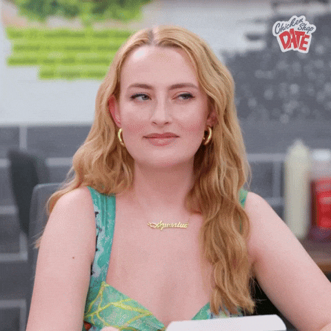 Video gif. Amelia Dimoldenberg, host of Chicken Shop Date, side-eyes and slightly squints as she nods lightly with a look of aggreement