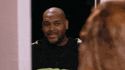 Reality TV gif. Brandon on Growing Up Hip Hop: Atlanta stands in doorway and smiles as he says, "I'm home." We cut to Debra Atney who looks back at him skeptically.