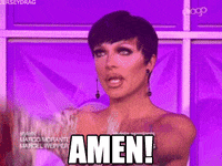 Reality TV gif. Raven in RuPaul's Drag Race wears a floral long sleeve one shoulder top, gazing upward and raising her arms above her. Text, "Amen!"