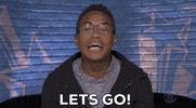 Reality TV gif. Sitting in front of a blue brick wall painted with stars, David on Big Brother says urgently, “Let’s go!”