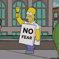 The Simpsons gif. Homer walks wide-eyed in the middle of a city street while ringing a bell in the air and wearing a sign that reads, "No Fear."  