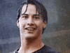 Celebrity gif. A young Keanu Reeves stands in the rain smiling. He raises up his arm and gives an enthusiastic thumbs up.
