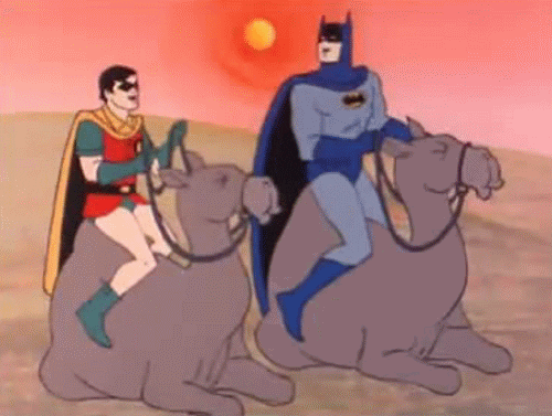 TV gif. Cartoon Batman and Robin sit on camels. They look at eachother and laugh with bouncing shoulders.