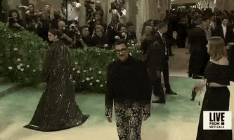 Met Gala 2024 gif. Camera on Dan Levy snap zooms out to reveal the chaos that surrounds him as he awkwardly wanders, looking around, unsure where he should go or what he should do.