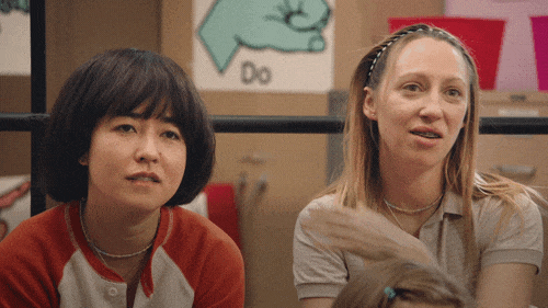 TV gif. Maya Erskine as Maya and Anna Konkle as Anna on Pen15. They're sitting next to each other and smile awkwardly while Anna pets her hair and says, "That's so true. Wow." 